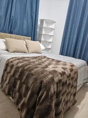 a bed with a blanket on it with blue curtains at Chya home in Marrakech