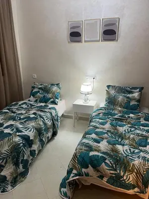 a bedroom with two beds and a table with a lamp at Appartement familial Marrakech in Marrakech