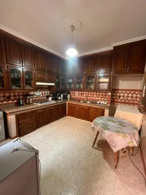 a kitchen with wooden cabinets and a table in it at Appartement familial Marrakech in Marrakech