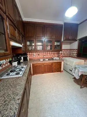 a kitchen with wooden cabinets and a stove top oven at Appartement familial Marrakech in Marrakech