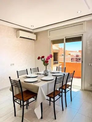 a dining room table with chairs and a vase of flowers at Appartement de luxe Marrakech - Targa in Marrakech