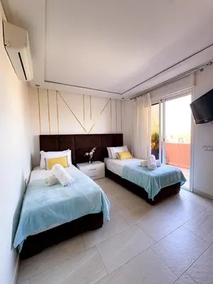 a bedroom with two beds and a large window at Appartement de luxe Marrakech - Targa in Marrakech