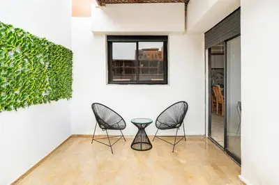 two chairs and a table in a room with a green wall at Horizon Cozy terrace and serenity in Marrakech