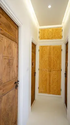 a hallway with two wooden doors and white walls at Majorelle Garden - Design apartment in Marrakech
