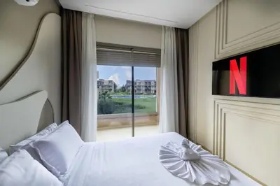 a bedroom with a large white bed with a large window at Prestigia Exceptional apartment with pool view in Marrakech