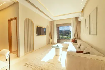 a living room with a couch and a table at Prestigia Exceptional apartment with pool view in Marrakech