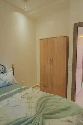 a bedroom with a bed and a wooden cabinet at Spacious Apartment with AC & Fast WiFi 5 Guests in Marrakech