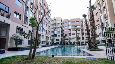 a courtyard with a pool in a building with palm trees at Appartement vue piscine & fitness à Guéliz in Marrakech
