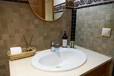 a bathroom sink with a bottle of wine and a mirror at Stylish Apartment with Pool in Marrakech in Marrakech
