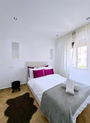 a white bedroom with a large bed with purple pillows at Villa nakhil in Marrakech