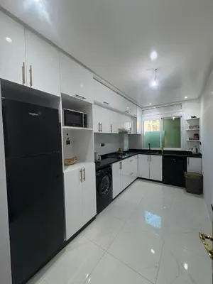 a kitchen with white cabinets and a black refrigerator at prestige 2 bedroom appartment in Marrakesh in Marrakech
