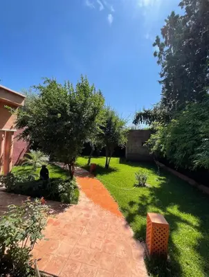 a garden with a brick path and trees and a house at Villa MyMa in Marrakech