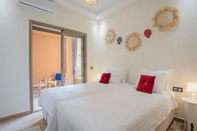 a white bedroom with a large white bed with red pillows at 2 bedroom apartment, 4 people, near Jardin Majorelle in Marrakech
