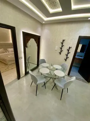 a dining room with a glass table and white chairs at Charmant cocon moderne in Marrakech