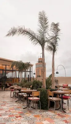 a restaurant with tables and chairs and palm trees at Stunning penthouse in city center in Marrakech