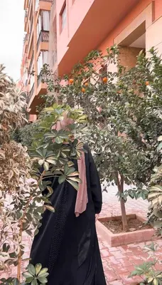 a woman standing next to a tree next to a building at Stunning penthouse in city center in Marrakech