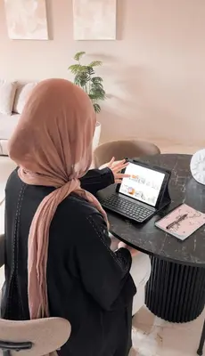 a woman sitting at a table with a laptop computer at Penthouse city center sdfghjhgfdsdfghjhgfdsdfghjhgfds in Marrakech