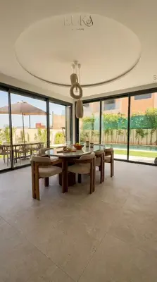 a dining room with a table and benches and windows at Villa Akenza Marrakech - Private Gym & Pool in Marrakech