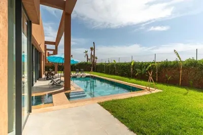 a swimming pool in a yard next to a house at Luxury Villa with Breakfast & Padel Access in Marrakech