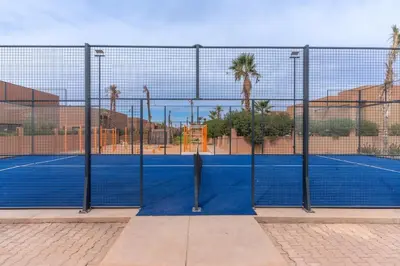 a tennis court with a net on a court at Luxury Villa with Breakfast & Padel Access in Marrakech