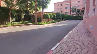 an empty street with palm trees and a pink building at Cozy 2-bedroom apartment & pool & wifi in Marrakech