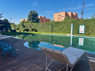 a swimming pool with chairs next to a building at Cozy 2-bedroom apartment & pool & wifi in Marrakech