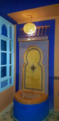 a room with a blue wall with a mirror and a chandelier at Riad Konouz in Marrakech