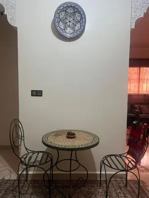 a table with two chairs and a plate on a wall at modern apartment, 10 minutes from the airport in Oulad Akkou