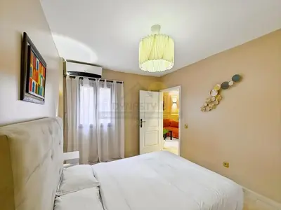 a bedroom with a white bed and a chandelier at Appartement neuf et chic Proche gare et CTM in Marrakech