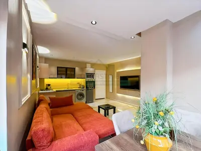 a living room with an orange couch and a kitchen at Appartement neuf et chic Proche gare et CTM in Marrakech