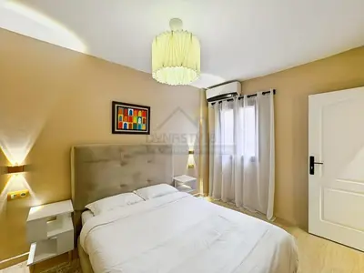 a bedroom with a large white bed and a chandelier at Appartement neuf et chic Proche gare et CTM in Marrakech