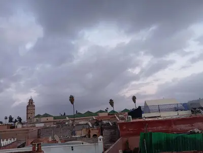 a view of a city with palm trees and a clock tower at riad medina rooftop 19 in Marrakech