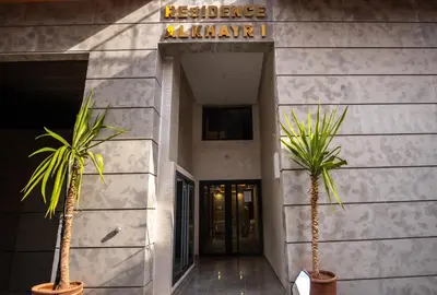 a building with two palm trees in front of it at Oasis Urban & Balcon - 5 min de l'aeroport in Marrakech