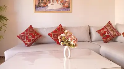 a couch with red pillows and a vase with a flower on it at Your chic retreat under the Marrakesh sun in Marrakech