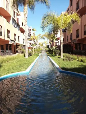 a pool in the middle of a yard with palm trees at Your chic retreat under the Marrakesh sun in Marrakech