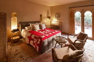 a bedroom with a bed with a red blanket and chairs at Riad Johara Marrakech in Marrakech