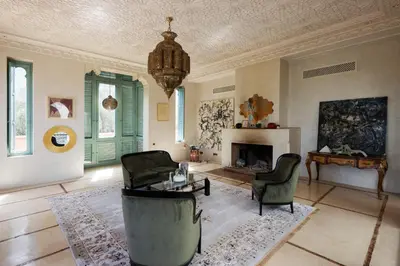 a living room with a fireplace and chairs and a chandelier at Riad Johara Marrakech in Marrakech