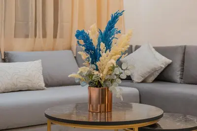 a vase of flowers on a table in front of a couch at 2 King Suites 2 Living Rooms 3 min Gueliz Carre Eden in Marrakech