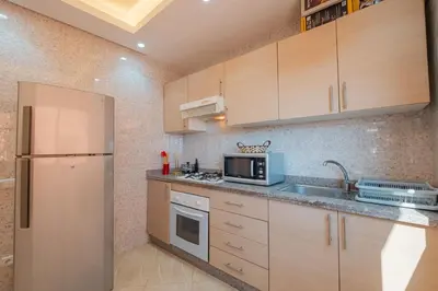 a kitchen with wooden cabinets and a stainless steel refrigerator at 2 King Suites 2 Living Rooms 3 min Gueliz Carre Eden in Marrakech