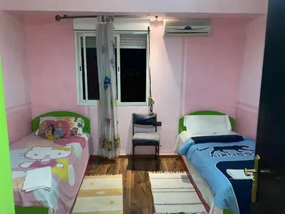 a bedroom with two beds and a window and a chair at Appartement Nomade in Marrakech