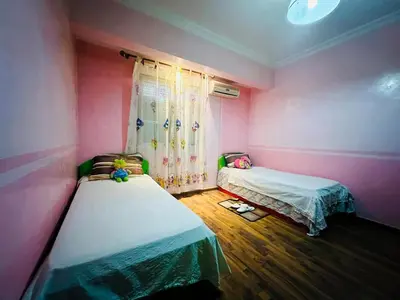 two beds in a room with pink walls and wooden floors at Appartement Nomade in Marrakech