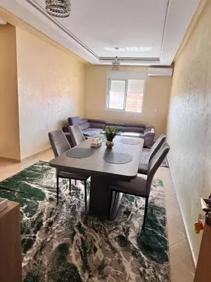 a dining room with a table and chairs on a rug at Apartmen rentals with M Z in Oulad Akkou