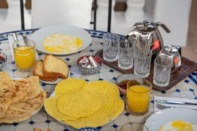a table topped with plates of food and glasses of orange juice at Riad Lalla Rachida in Medina Heart Of Marrakech B&B in Marrakech