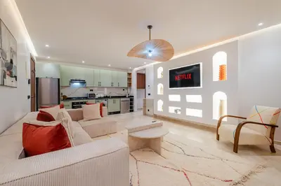 a living room with a white couch and a kitchen at Stylish Downtown Apartment Optical Fiber Included in Marrakech