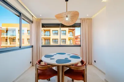 a table and chairs in a room with a window at Stylish Downtown Apartment Optical Fiber Included in Marrakech