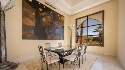 a dining room with a glass table and chairs at KAZA BELLA - Palais Les Orchidées in Marrakech