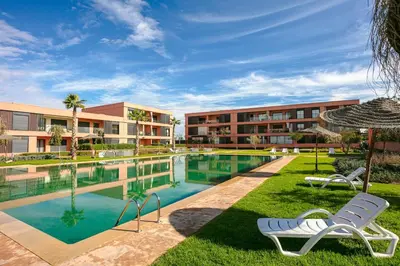 a resort pool with two chairs and an umbrella at The Velvet Retreat - Marrakech in Marrakech
