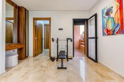 a gym with a chair in the middle of a room at Grand duplex 4 ch - Piscine - Marrakech in Marrakech