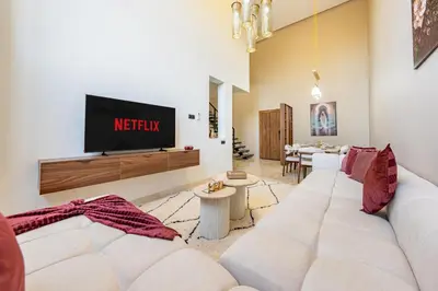 a living room with a white couch and a tv at Grand duplex 4 ch - Piscine - Marrakech in Marrakech