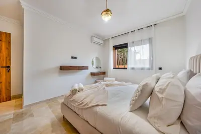 a white bedroom with a bed and a window at Grand duplex 4 ch - Piscine - Marrakech in Marrakech